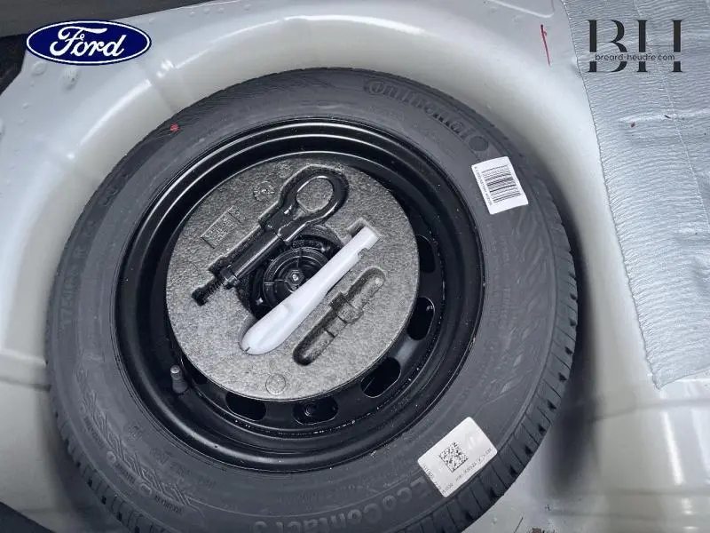 Gros plan sur la roue de secours 14 pouces noire dans le coffre d'une Ford Fiesta Blanc Glacier 2022.