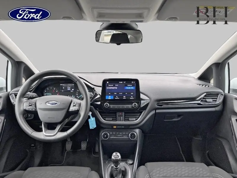 Vue frontale de l’habitacle noir de la Ford Fiesta 2022 avec volant cuir, écran tactile et boîte manuelle visible.