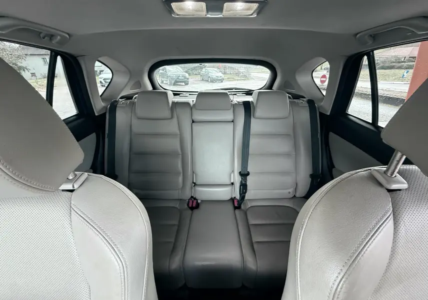 Vue intérieure arrière du Mazda CX-5 2013 montrant les sièges en cuir gris clair avec appuie-têtes et ceinture de sécurité.