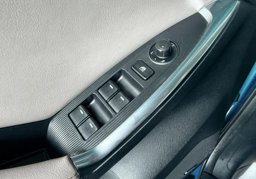 Gros plan sur la commande des vitres électriques côté conducteur du Mazda CX-5 bleu, avec réglage des rétroviseurs.