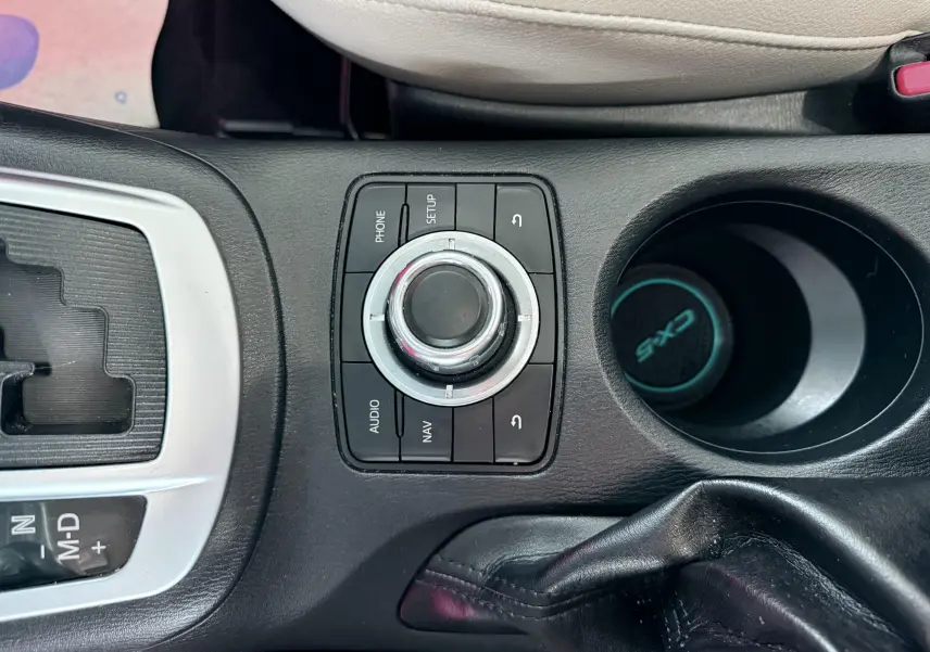 Gros plan sur la console centrale noire du Mazda CX-5 bleu 2013, avec molette de commande et porte-gobelet marqué CX-5.