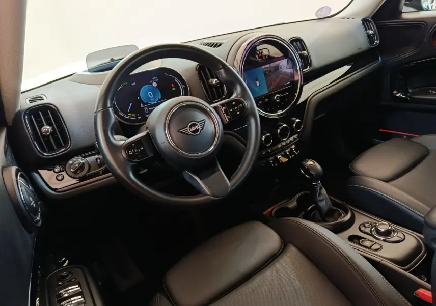 Vue intérieure côté conducteur du MINI Countryman Cooper SE noir, avec tableau de bord digital et écran central tactile rond.