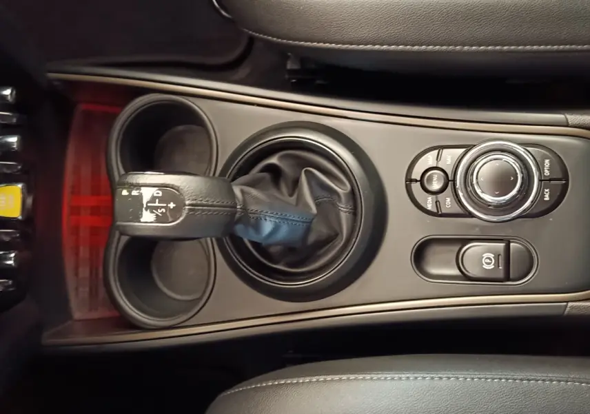 Vue rapprochée de la console centrale noire du MINI Countryman Cooper SE avec levier de vitesses et commandes multifonctions.