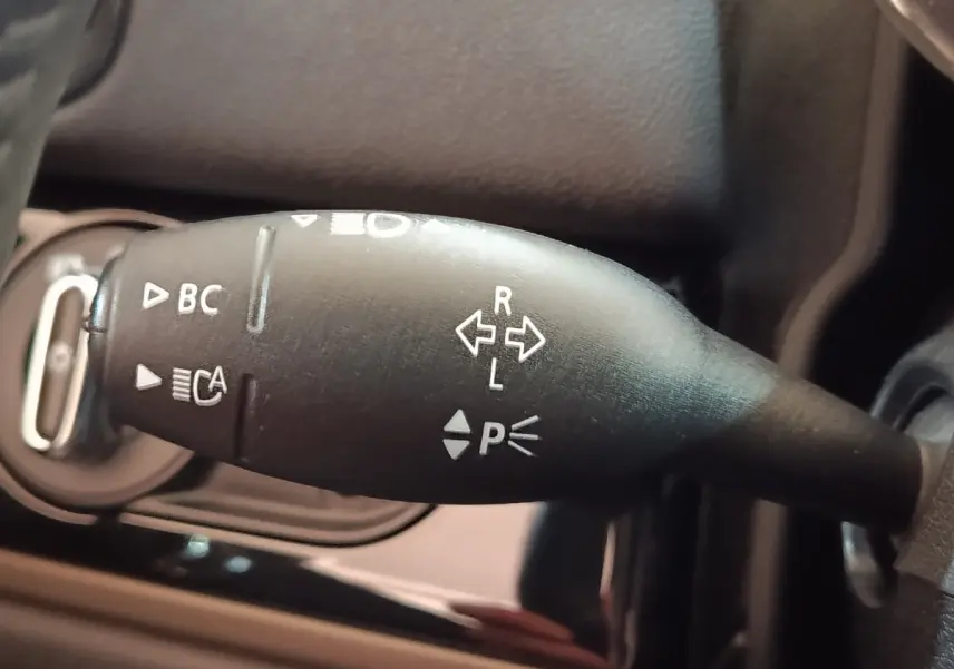 Gros plan sur la commande de clignotants noire du MINI COUNTRYMAN Cooper SE 2023, avec symboles blancs visibles.