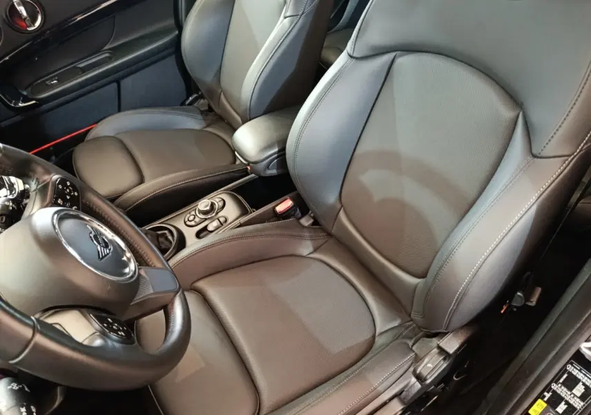 Vue intérieure rapprochée côté conducteur du MINI Countryman Cooper SE avec sièges cuir noirs et volant multifonctions.