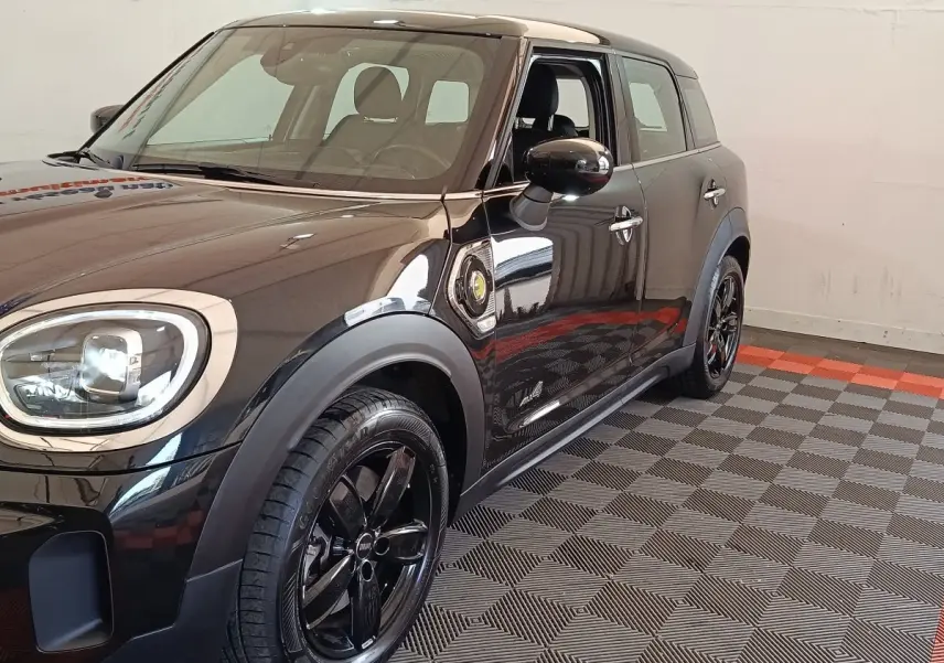 Vue 3/4 avant droit d'une MINI Countryman Cooper SE noire avec jantes noires et logo électrique sur l'aile.