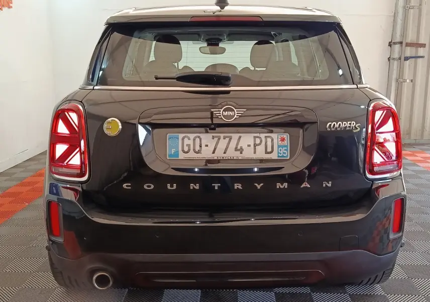 Vue arrière d'une MINI Countryman Cooper S noire avec feux LED et logo hybride jaune visible à gauche.