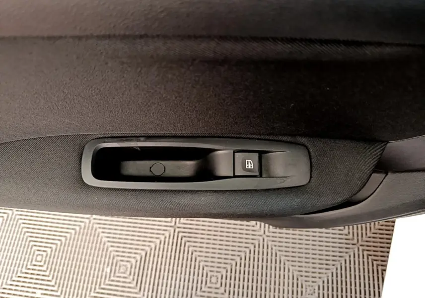 Gros plan sur la commande de lève-vitre côté intérieur d'une Renault Mégane Business E-Tech blanche.