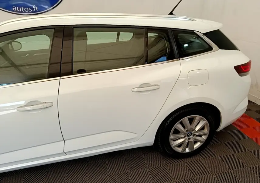 Profil droit d'une Renault Mégane Business E-Tech hybride rechargeable blanche, avec jantes alliage et vitres teintées.