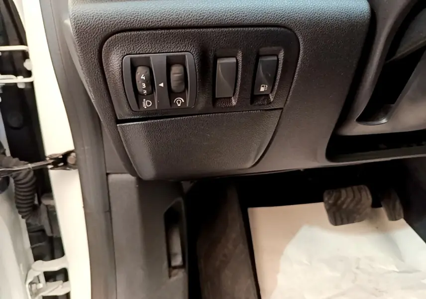 Vue rapprochée côté conducteur de la Renault Mégane Business E-Tech hybride blanche, montrant les commandes d’éclairage et ouverture carburant.