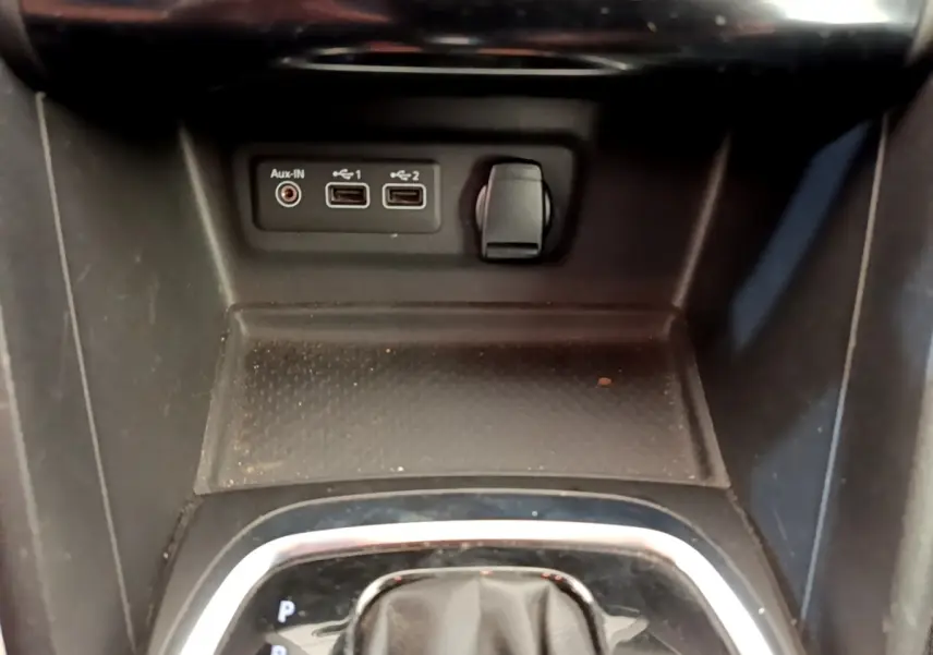 Gros plan sur la console centrale noire de la Renault Mégane Business E-Tech hybride, avec ports USB et prise auxiliaire.