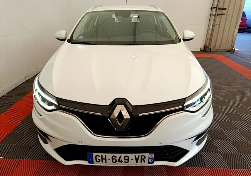 Vue avant d'une Renault Mégane Business E-Tech hybride rechargeable blanche avec phares LED allumés dans un garage.