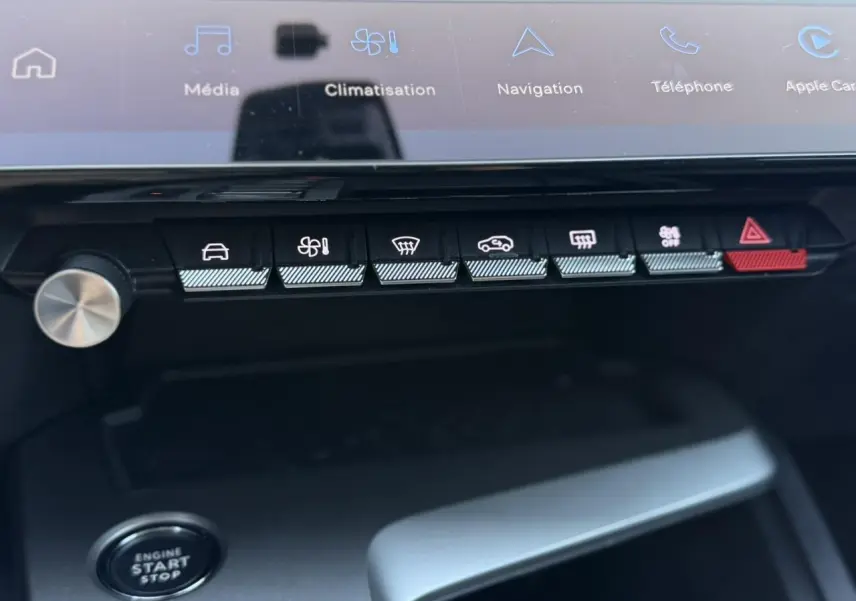 Vue rapprochée du tableau de bord de la Peugeot 308 Hybrid 2025, montrant les commandes de climatisation et démarrage.