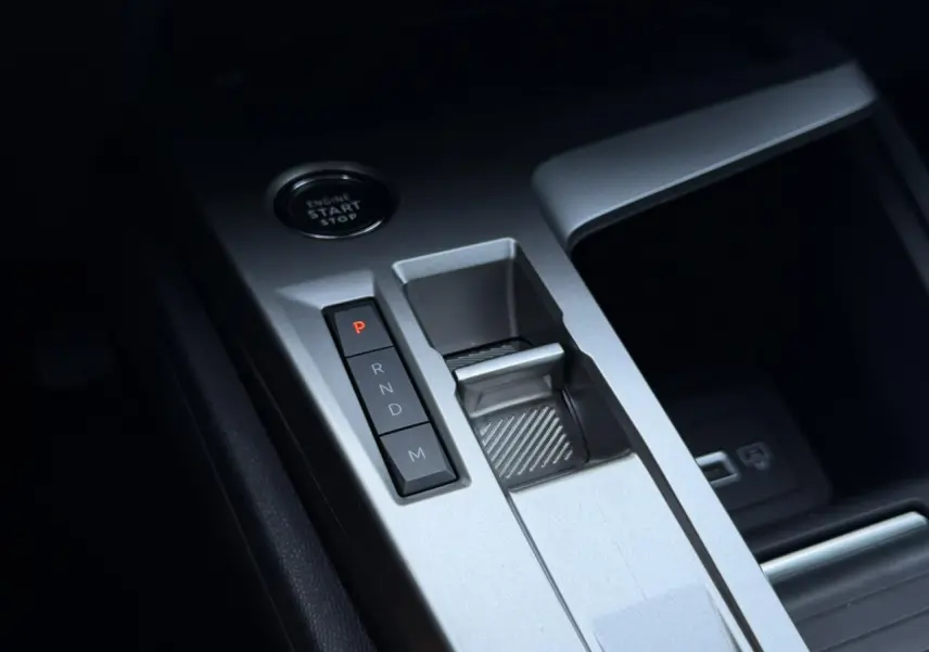 Gros plan sur la console centrale argentée de la Peugeot 308 Hybrid 2025 avec boutons de boîte auto et bouton start/stop.