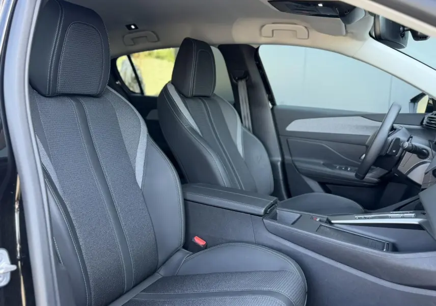 Vue intérieure côté gauche des sièges avant en sellerie tri matières TEP/tissu gris et noir de la Peugeot 308 Hybrid 2025.