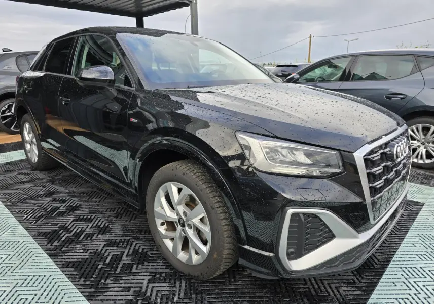 Audi Q2 noir mythic vue 3/4 avant droit sous pluie avec jantes aluminium et calandre S-Line sportive