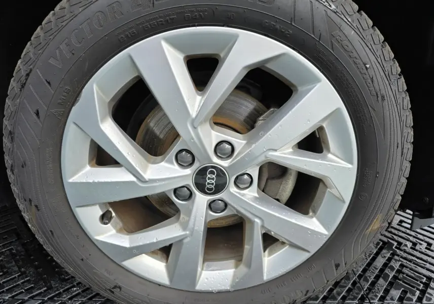 Gros plan sur la jante aluminium 5 branches doubles de l'Audi Q2 35 TFSI 2023 noir mythic avec pneu toutes saisons.