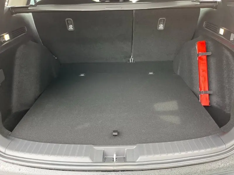 Coffre spacieux du Honda CR-V 2024 blanc platine, vue intérieure arrière avec triangle de signalisation rouge fixé à droite.