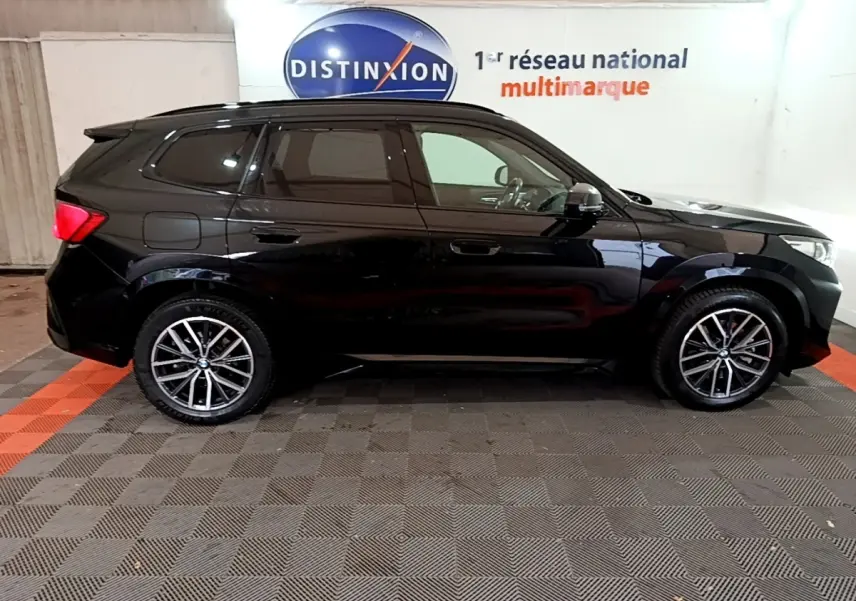 BMW X1 xDrive23i M Sport noir vu de profil côté gauche, avec jantes alliage et vitres teintées.