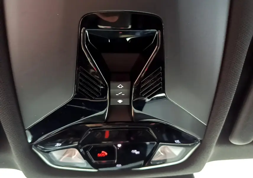 Vue en gros plan du plafonnier noir brillant avec bouton SOS et commandes d'éclairage intérieur d'un BMW X1 2023.