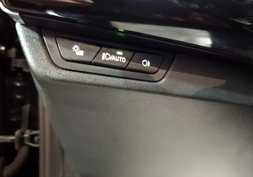 Boutons de commande des phares avec réglage automatique sur tableau de bord noir du BMW X1 xDrive23i M Sport 2023.