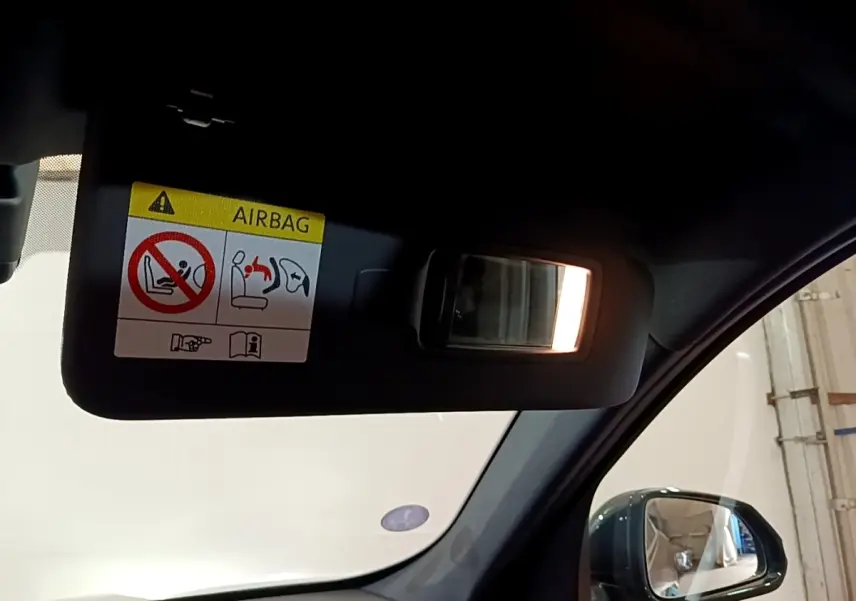 Détail du pare-soleil côté conducteur avec miroir éclairé et étiquette airbag dans un BMW X1 noir 2023.