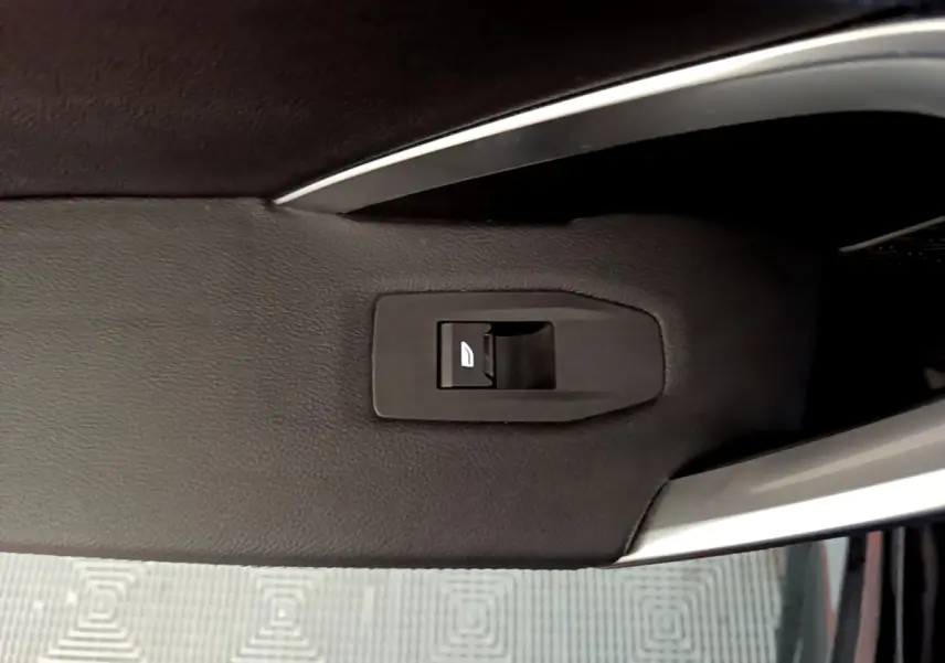 Bouton de commande de vitre sur la porte intérieure noire d'un BMW X1 xDrive23i M Sport 2023.