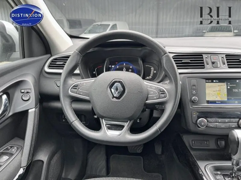 Vue intérieure centrée sur le volant cuir multifonction d’un Renault Kadjar gris platine avec écran tactile et tableau de bord numérique.