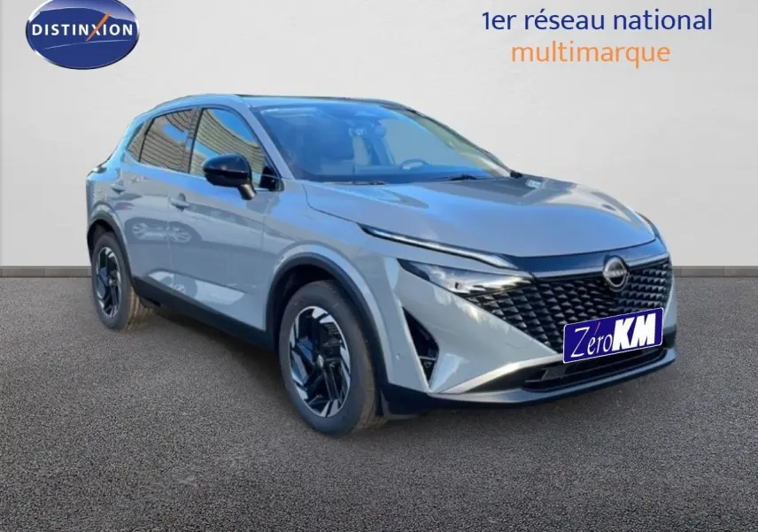Nissan Qashqai 2025 gris argile métal en 3/4 avant, avec calandre noire et jantes au design moderne.