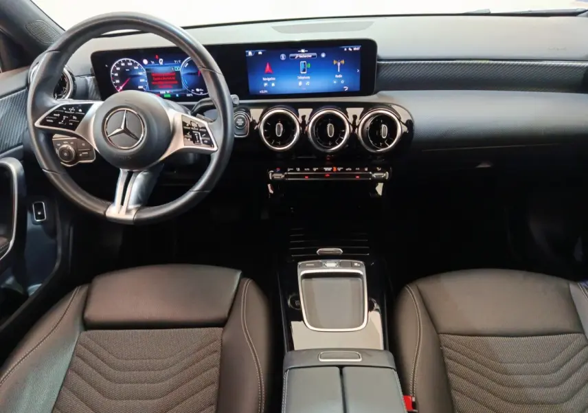 Vue intérieure avant de la Mercedes Classe A 250 e Business Line 2023, volant cuir alu et écran tactile central lumineux.