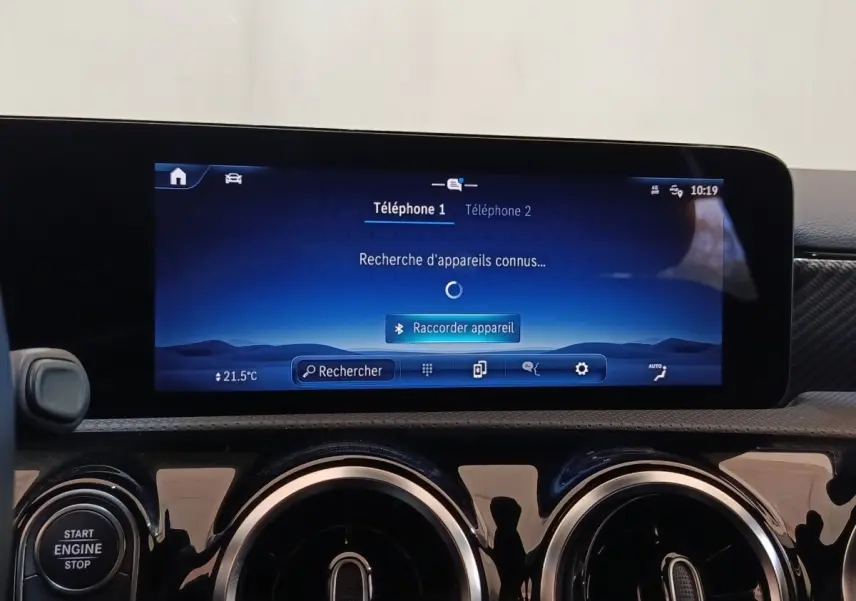 Vue intérieure du tableau de bord de la Mercedes Classe A 250 e Business Line 2023 avec écran tactile central et aérateurs ronds chromés.