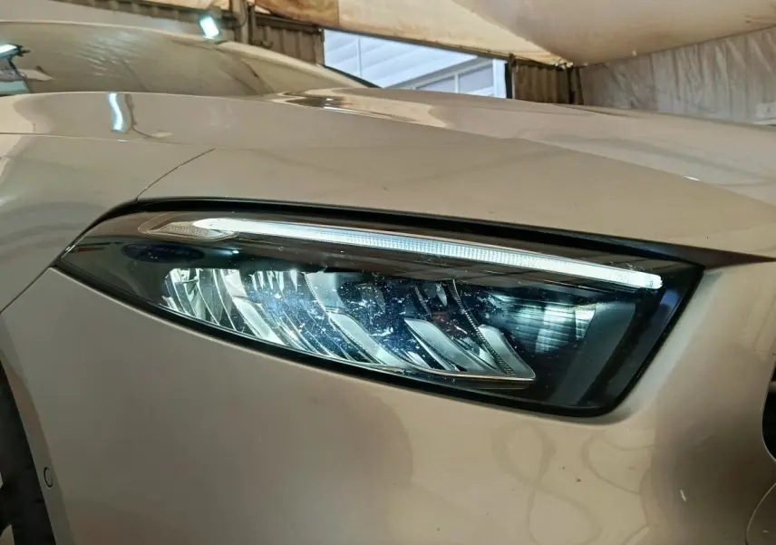 Gros plan sur le phare avant droit gris clair d'une Mercedes Classe A 250 e Business Line 2023 avec LED distinctive.
