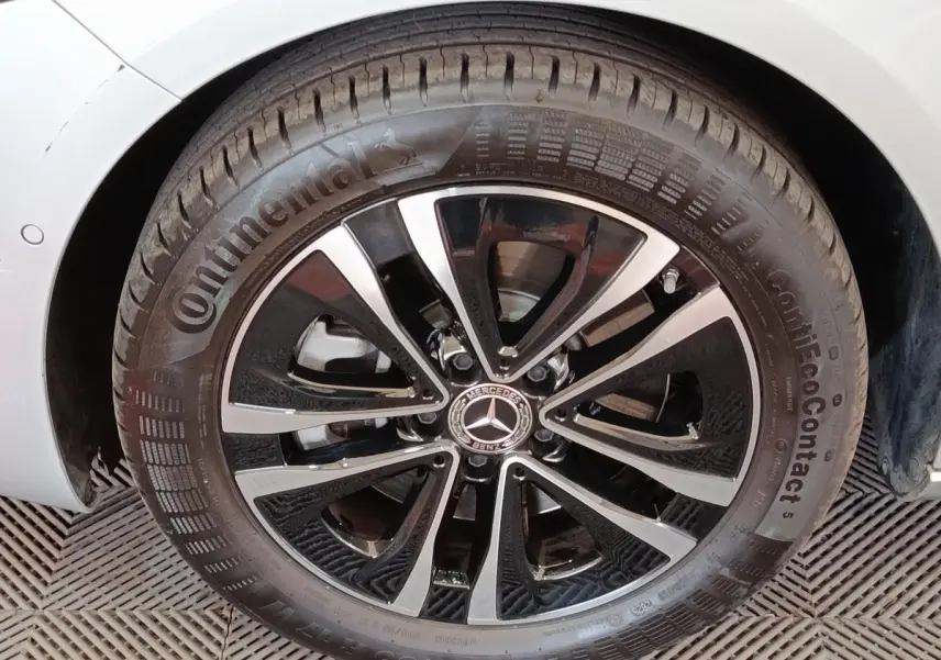 Gros plan sur la jante alliage noir et argentée d'une Mercedes Classe A gris clair, roue avant droite visible.