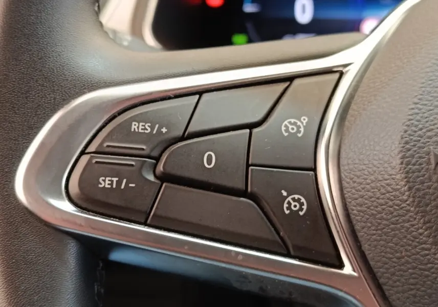 Gros plan sur les commandes du régulateur de vitesse au volant cuir du Renault Captur gris clair Intens E-TECH 2021.