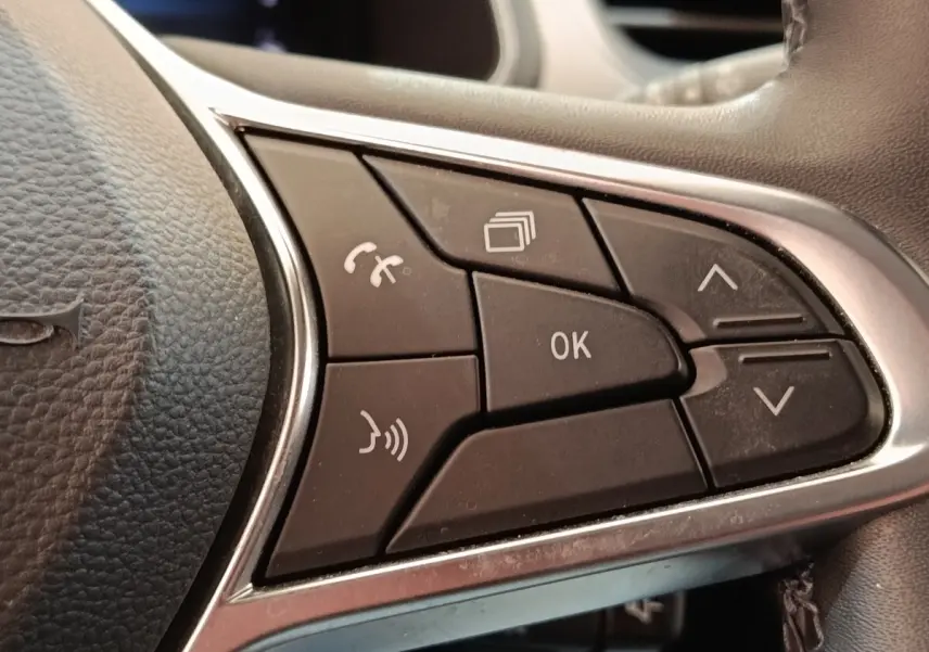 Gros plan sur les commandes multifonctions noires du volant cuir synthétique du Renault Captur gris clair, version Intens E-TECH 2021.
