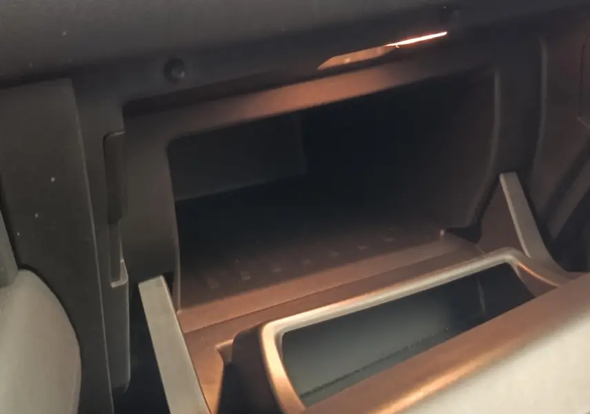 Gros plan sur la boîte à gants ouverte de la Renault Captur Intens E-TECH 2021, intérieur noir avec éclairage ambiant.