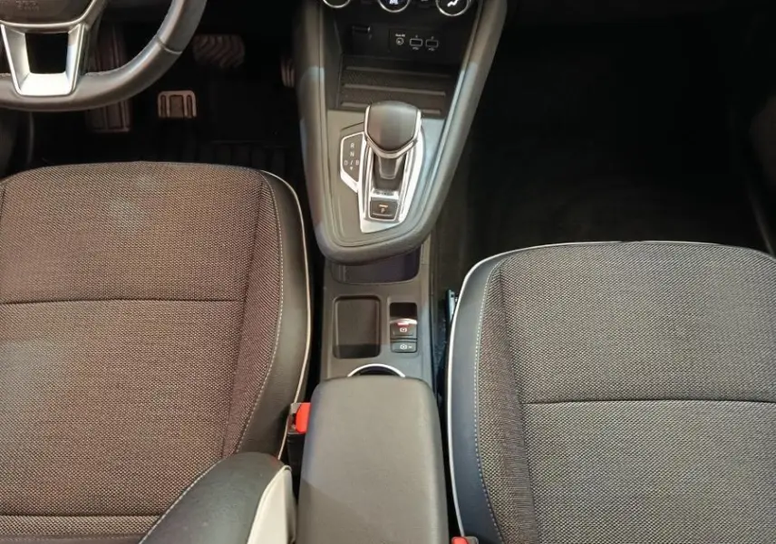 Vue intérieure centrée sur la console centrale et les sièges avant noirs du Renault Captur Intens E-TECH 2021.