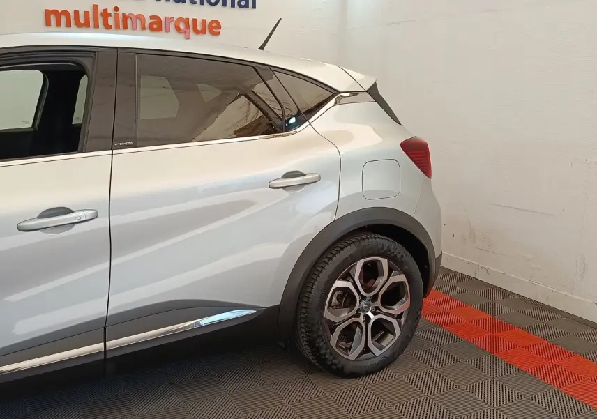 Vue côté droit arrière du Renault Captur gris clair Intens E-TECH Plug-in 160 avec détails de porte et jante visibles.