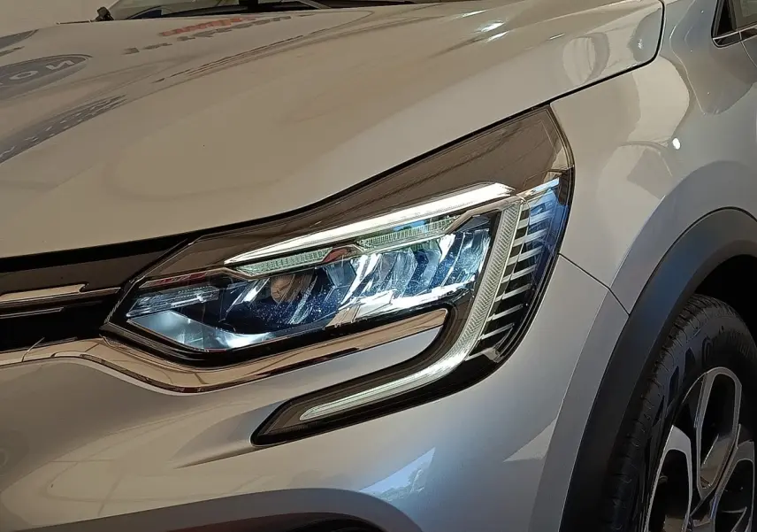 Gros plan sur le phare avant droit et la roue d’un Renault Captur gris clair Intens E-TECH Plug-in 2021.