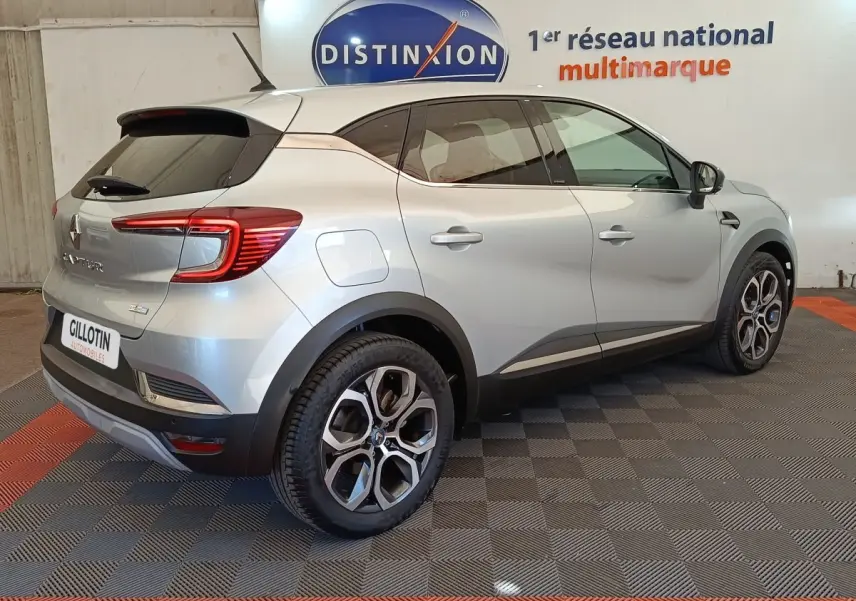 Vue 3/4 arrière droite d’un Renault Captur Intens E-TECH gris clair avec jantes alliage et vitres teintées.