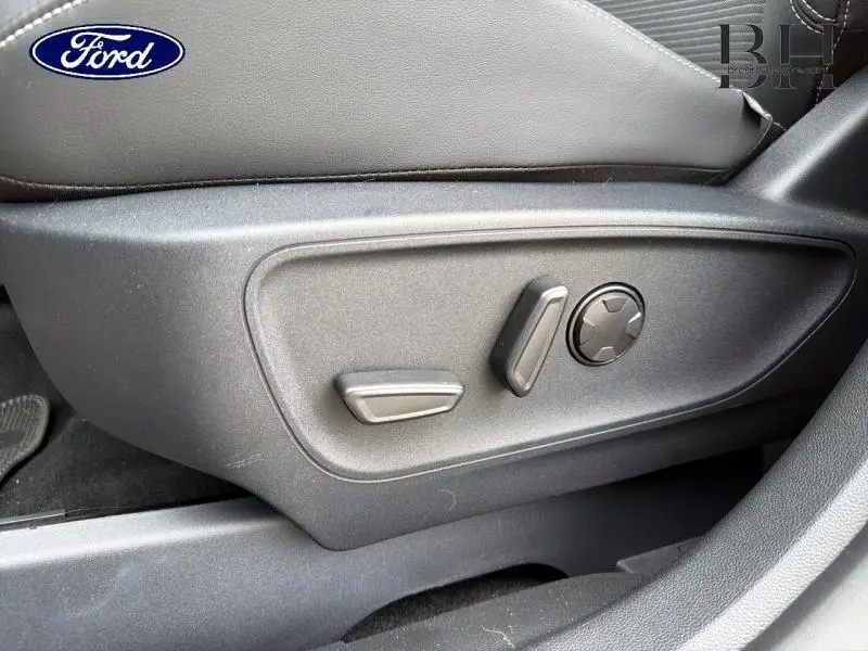 Détail des commandes électriques du siège conducteur gris du Ford Kuga 2026, vue latérale côté gauche.