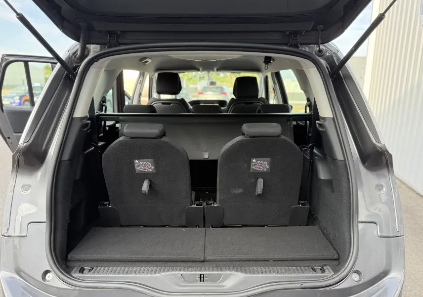 Vue arrière du coffre ouvert d'un Citroën Grand C4 Spacetourer gris, montrant les sièges rabattus et l'intérieur spacieux.