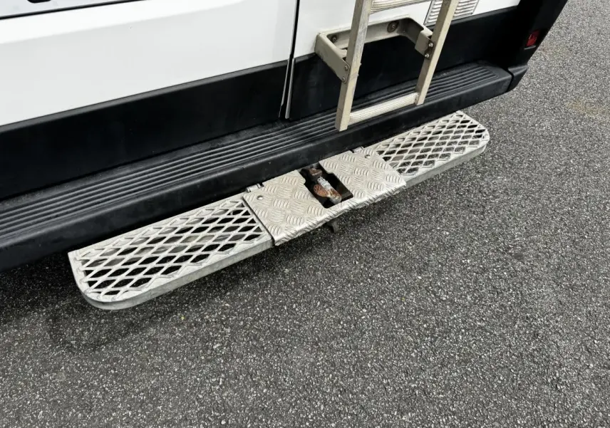 Vue rapprochée du marchepied arrière en métal sur la partie basse arrière droite du Citroën Jumper blanc.
