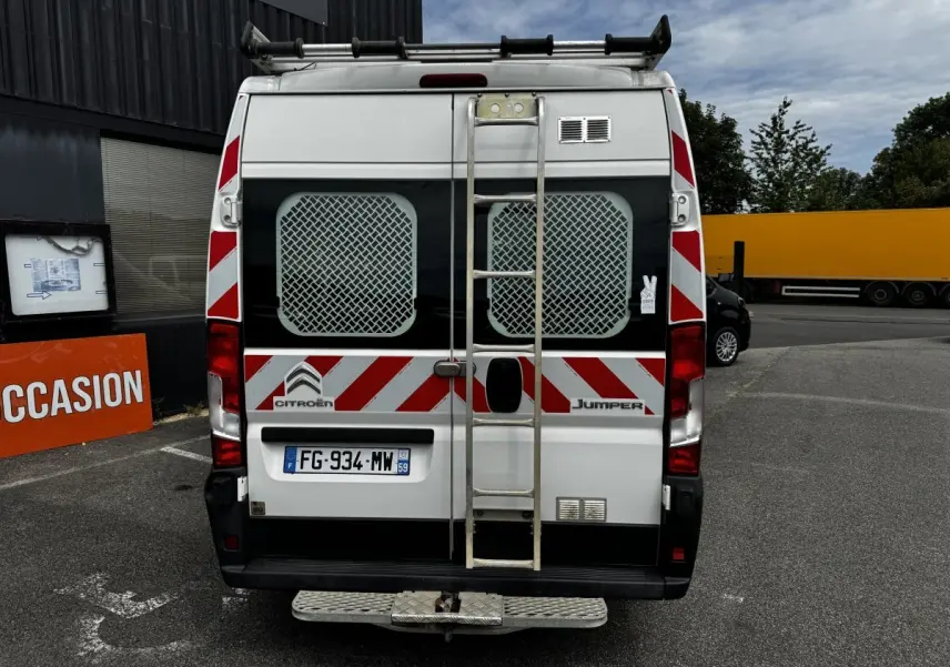Vue arrière d’un Citroën Jumper blanc 2019 avec échelle métallique centrale et bandes rouges réfléchissantes.