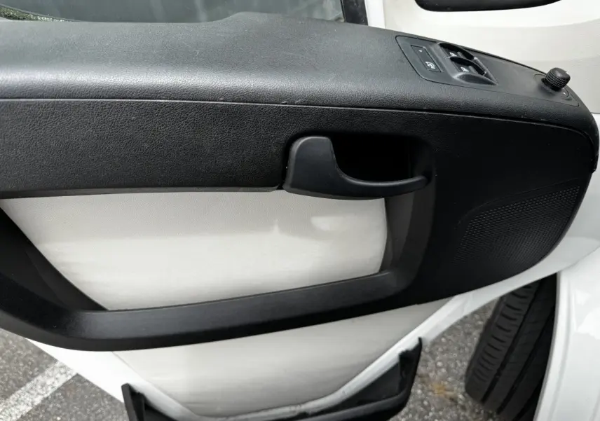 Gros plan sur la porte intérieure avant droite blanche du Citroën Jumper avec poignée et commandes de vitres noires.