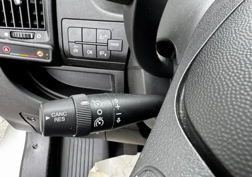 Gros plan sur la commande de régulateur de vitesse à gauche du volant dans l’habitacle du Citroën Jumper blanc.