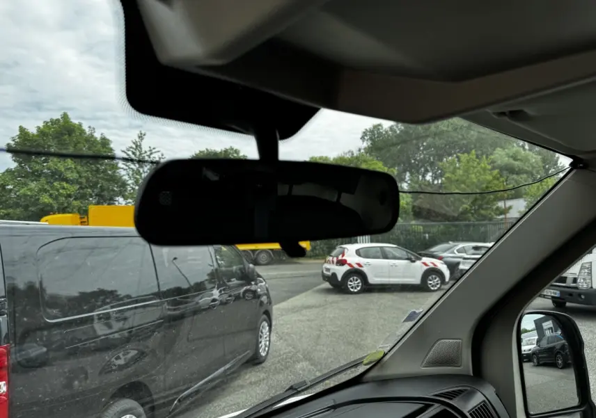 Vue intérieure depuis le siège conducteur du Citroën Jumper blanc, avec rétroviseur et tableau de bord partiellement visibles.