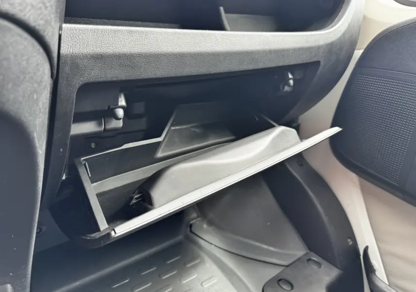 Gros plan sur la boîte à gants ouverte côté passager du Citroën Jumper blanc, intérieur noir et beige.