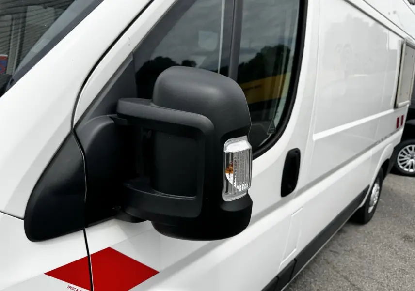 Vue de côté droit rapprochée sur le rétroviseur noir d’un utilitaire blanc Citroën Jumper 2019 avec marquage rouge.
