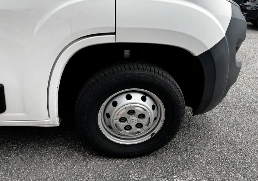 Gros plan sur la roue avant droite en jante acier argentée du Citroën Jumper blanc, avec partie de l'aile et pare-chocs noir visible.